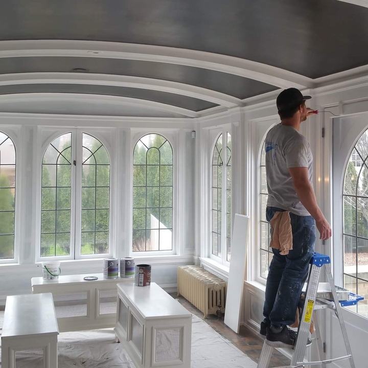 Sunroom in progress: cutting in trim under a charcoal barrel ceiling